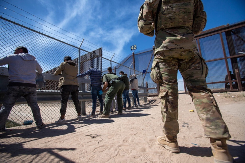 A Texas National Guardsman observes as Border Patrol agents pat down migrants who have surrendered themselves for processing, May 10, 2023. (Photo by Corrie Boudreaux for Source NM)